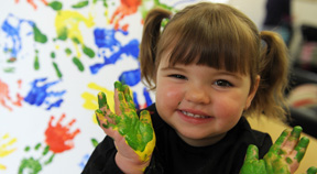 A toddler smiling with paint on her hands