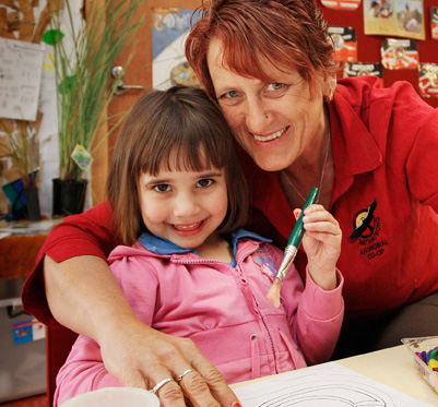 Young girl painting with her teacher. Young girl painting with her teacher.