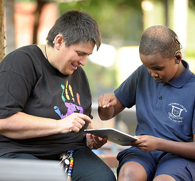 Teacher and young deaf student learning on an iPad.