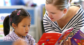 A female teacher helping a student read