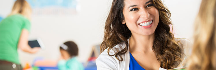 Teacher in the foreground, and students learning in the background.