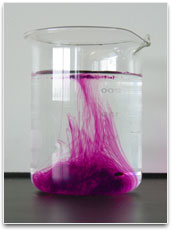 A beaker showing potassium permanganate crystals dissolving in a clear liquid.
