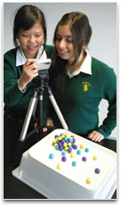 2 students are taking stop frame images of marble sized plasticine balls.