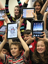 Class of students holding iPads above their heads