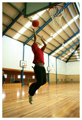 Student shooting a basketball midair in stadium