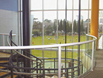 Interior of school building showing circular stairwell with tall glass windows