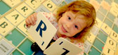A young girl holding up two Scrabble letters