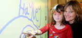 A mother and child pointing at a whiteboard that has writing on it