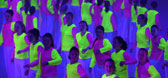 Large group of students in glowing costumes dancing