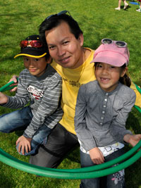 girl and boy playing with hulla hoops with their dad