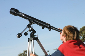 Young boy outside with telescope