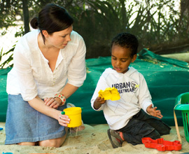 Kindergarten teacher in sandpit with child 