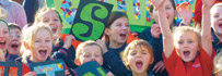 Children holding signs that spell out shine