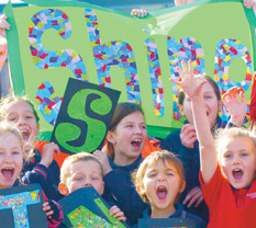 Children holding posters of letters to spell out SHINE
