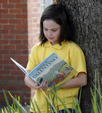 Girl reading against a tree