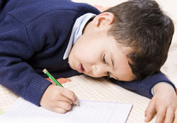 Boy lying down writing in book