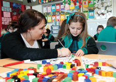 Teacher helping girl with work at a desk