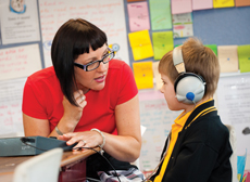 Learning Aide working with boy wearing headphones
