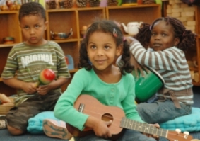 group of three young children playing musical instruments