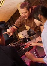 a teacher pointing to a student's computer screen