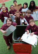 Kids putting cardboard into a recycling bin