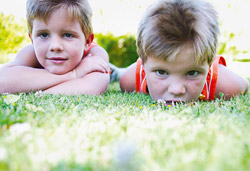 Twin boys laying on grass