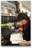 Person reading a text book next to a laptop