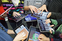 Students standing around in a circle using iPads