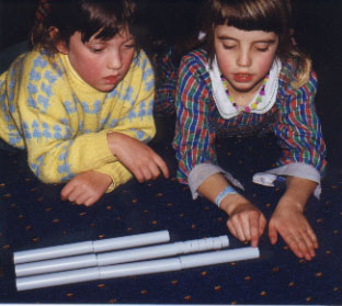 Students comparing various sized sections of plastic pipe