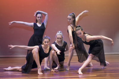 five secondary school-aged girls in black dresses pose  in dancing style