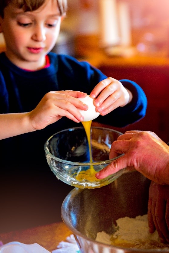 child breaking eggs into a bowl
