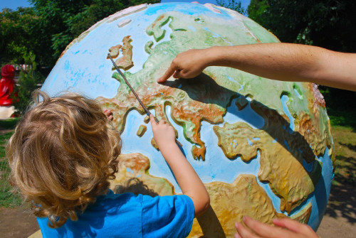 child pointing at a world globe
