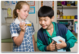 Students holding handwind torch & solar cell connected to portable battery radio