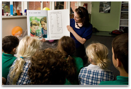 Group of students clustered around teacher reading a big book on a science theme