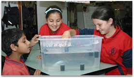 Three students are experimenting with floating film canisters.