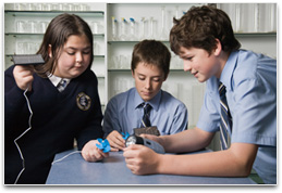 Students with mechanical handwind torch & solar cell connected to portable radio