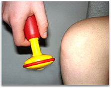 A student using a small plastic hammer to investigate knee reflex response