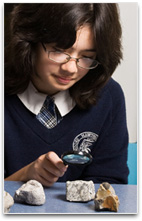 Student viewing a rock through magnifying glass