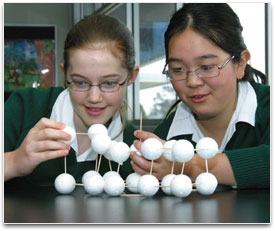 Two students building a molecule using 15 polystyrene balls and toothpicks.