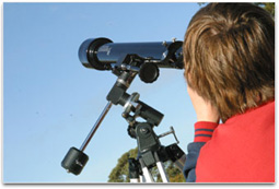 A student is looking through a telescope at the daytime sky.