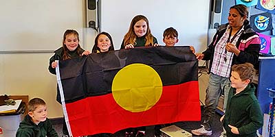 Bruthen Primary School students and teacher Nikki Hood hold an Aboriginal flag