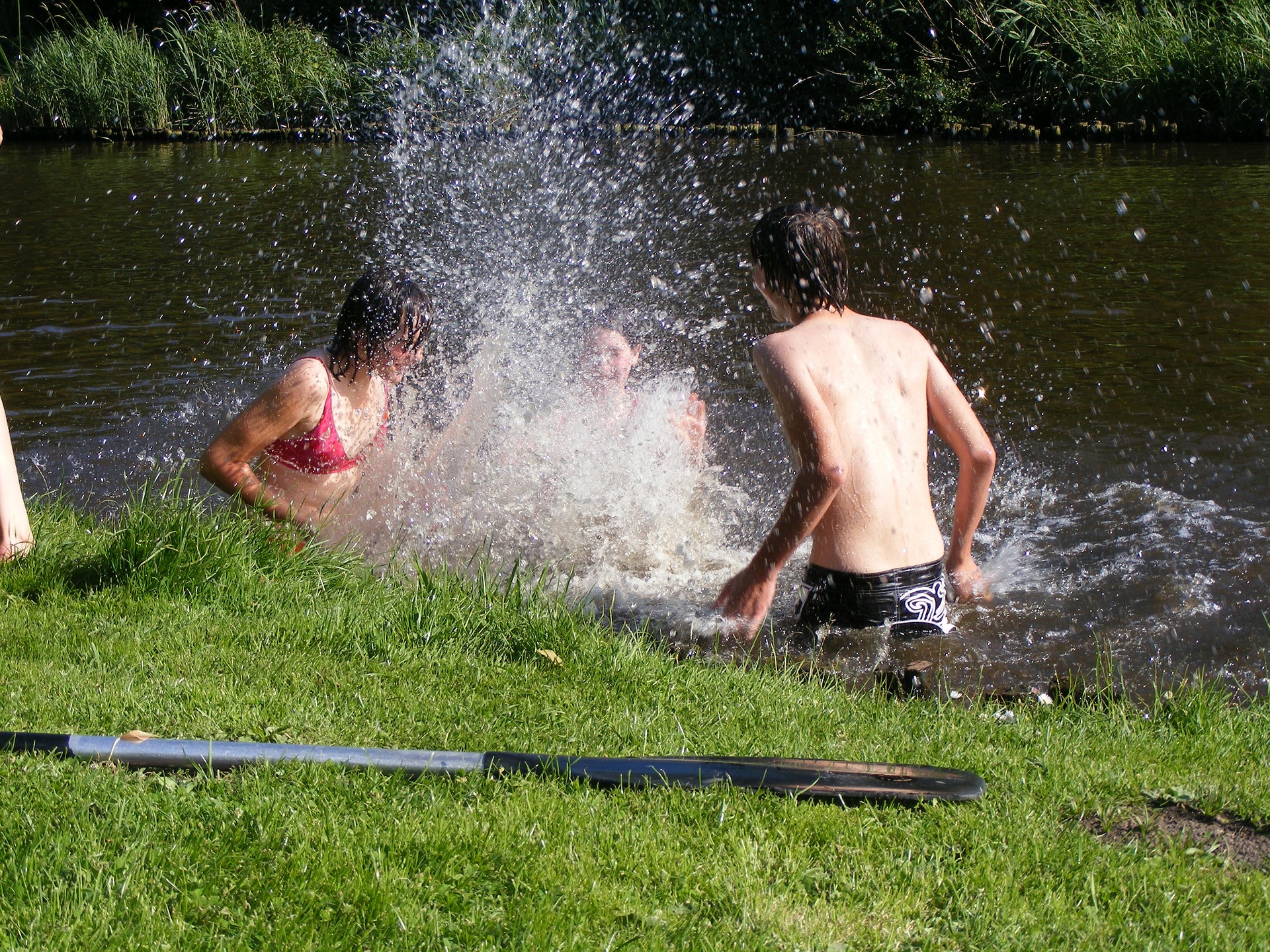 A photograph of three teenagers splashing around in a river